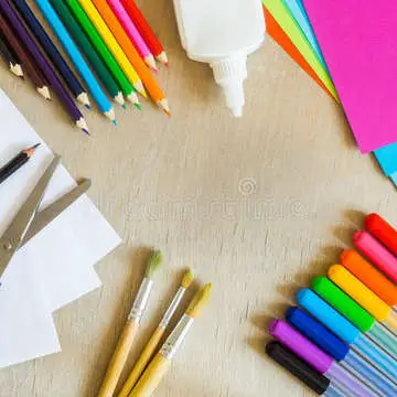Colored paper felt tip pens pencils brushes wooden background painting scissors glue 63553092